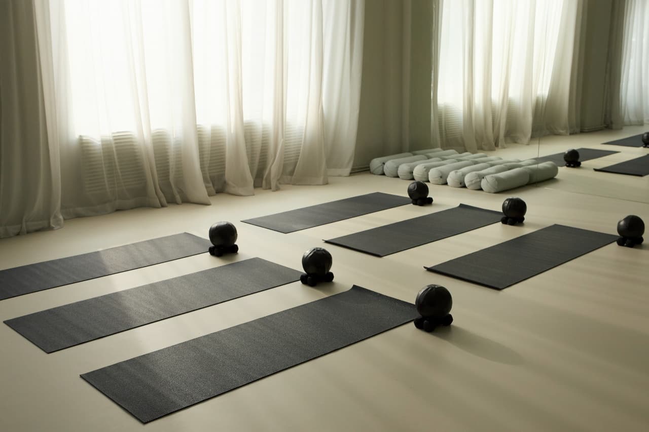 Black yoga mats laid out in a bright studio